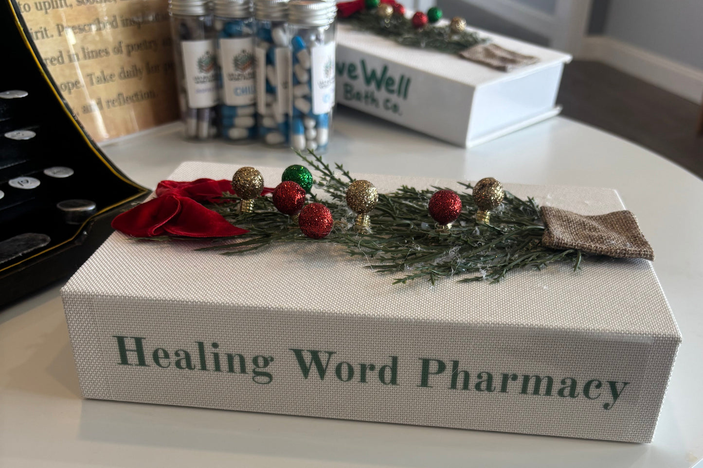 Decorative box labeled 'Healing Word Pharmacy' with a wreath on top, placed on a surface.