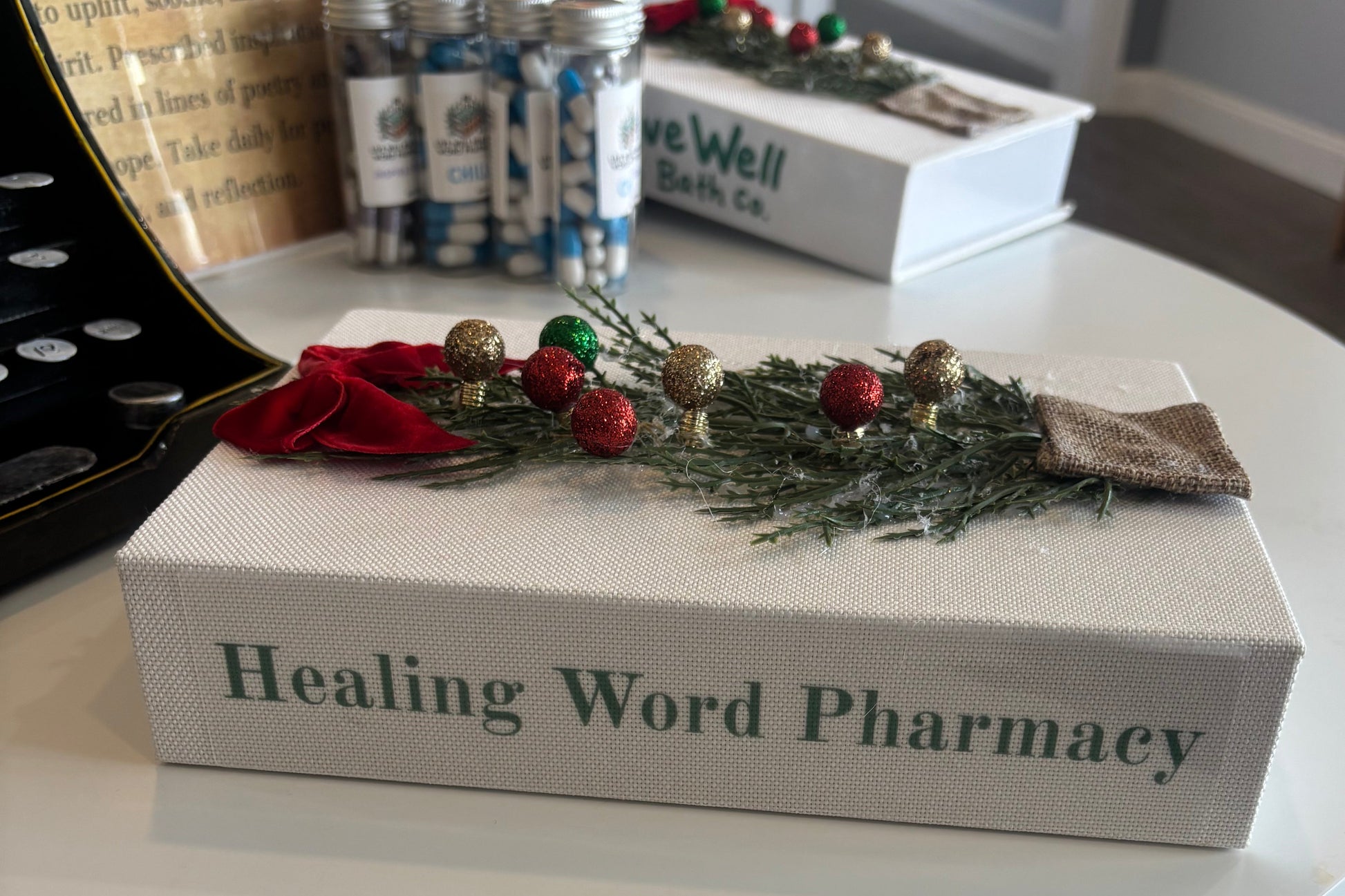Decorative box labeled 'Healing Word Pharmacy' with a wreath on top, placed on a surface.